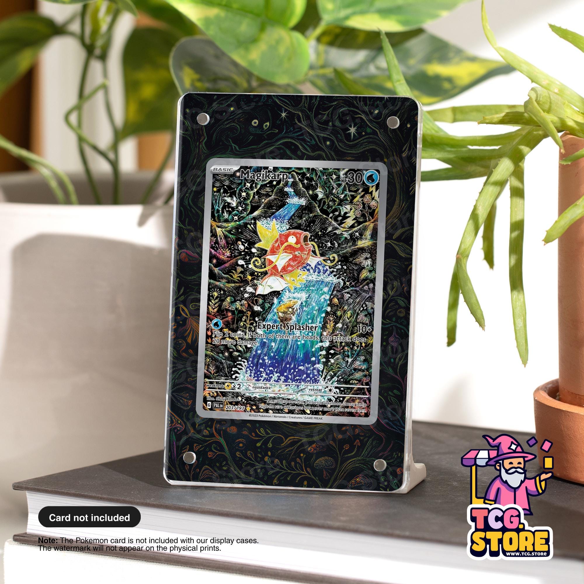 a framed Pokémon card on a table, surrounded by potted plants.