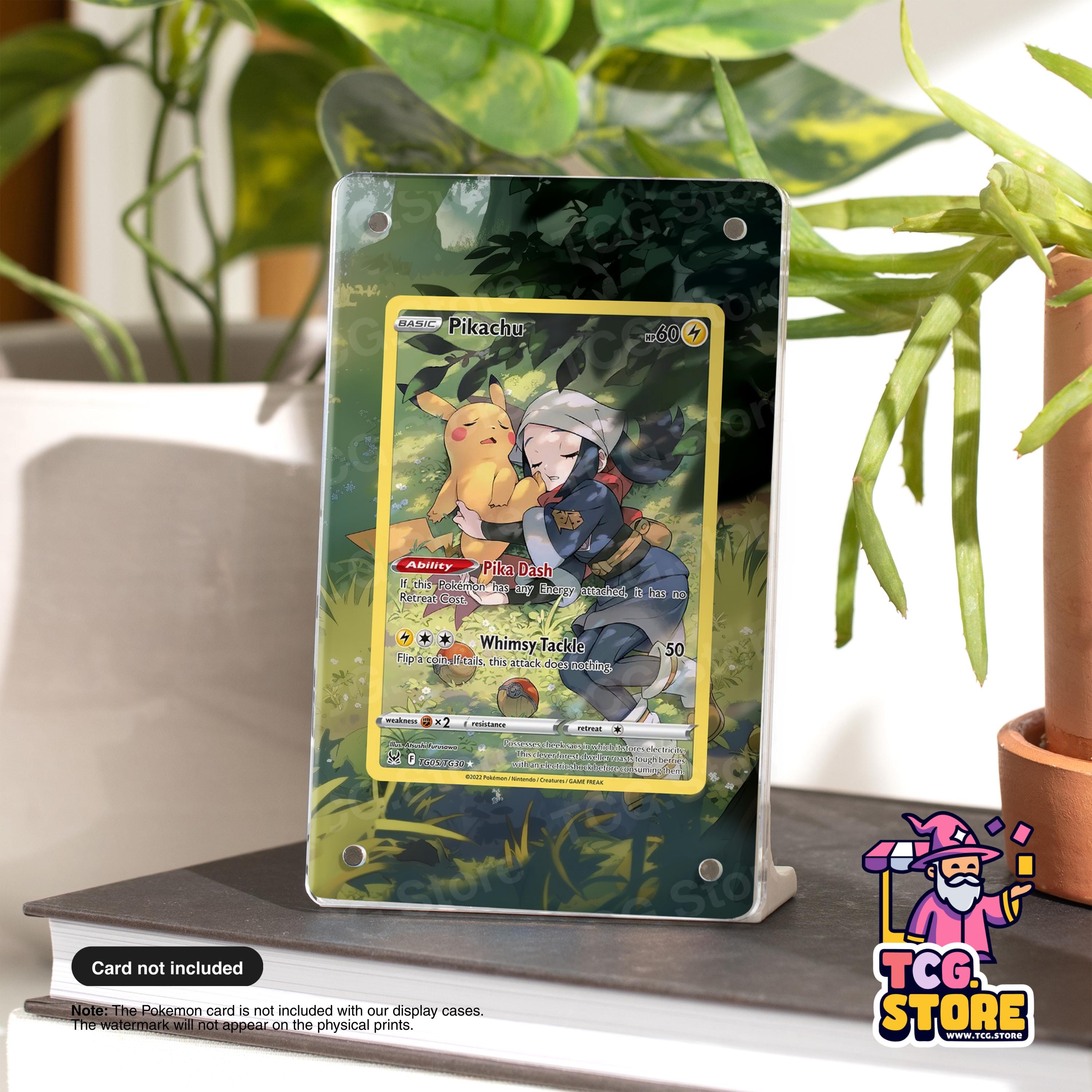 A Pokémon card featuring Pikachu and Whimsical is displayed on a stand, with a potted plant in the background.