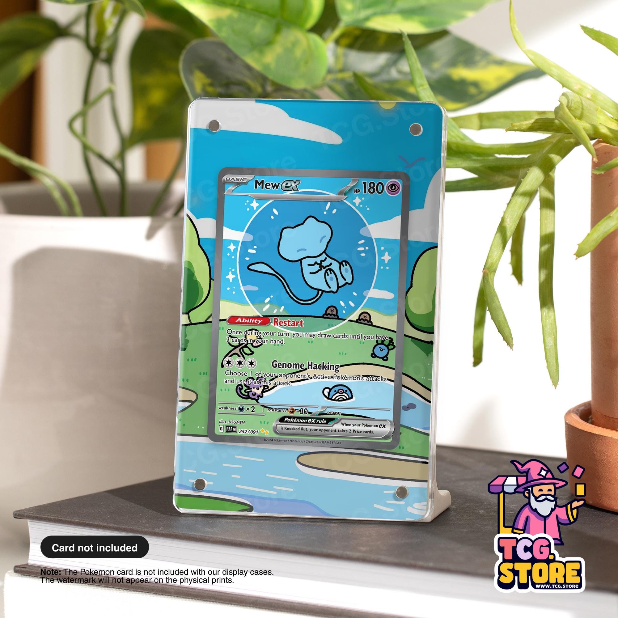 A Pokémon card display case featuring a Pokémon card with a blue background and a cartoon Pokémon character. The Pokémon card is placed on a table next to a potted plant.
