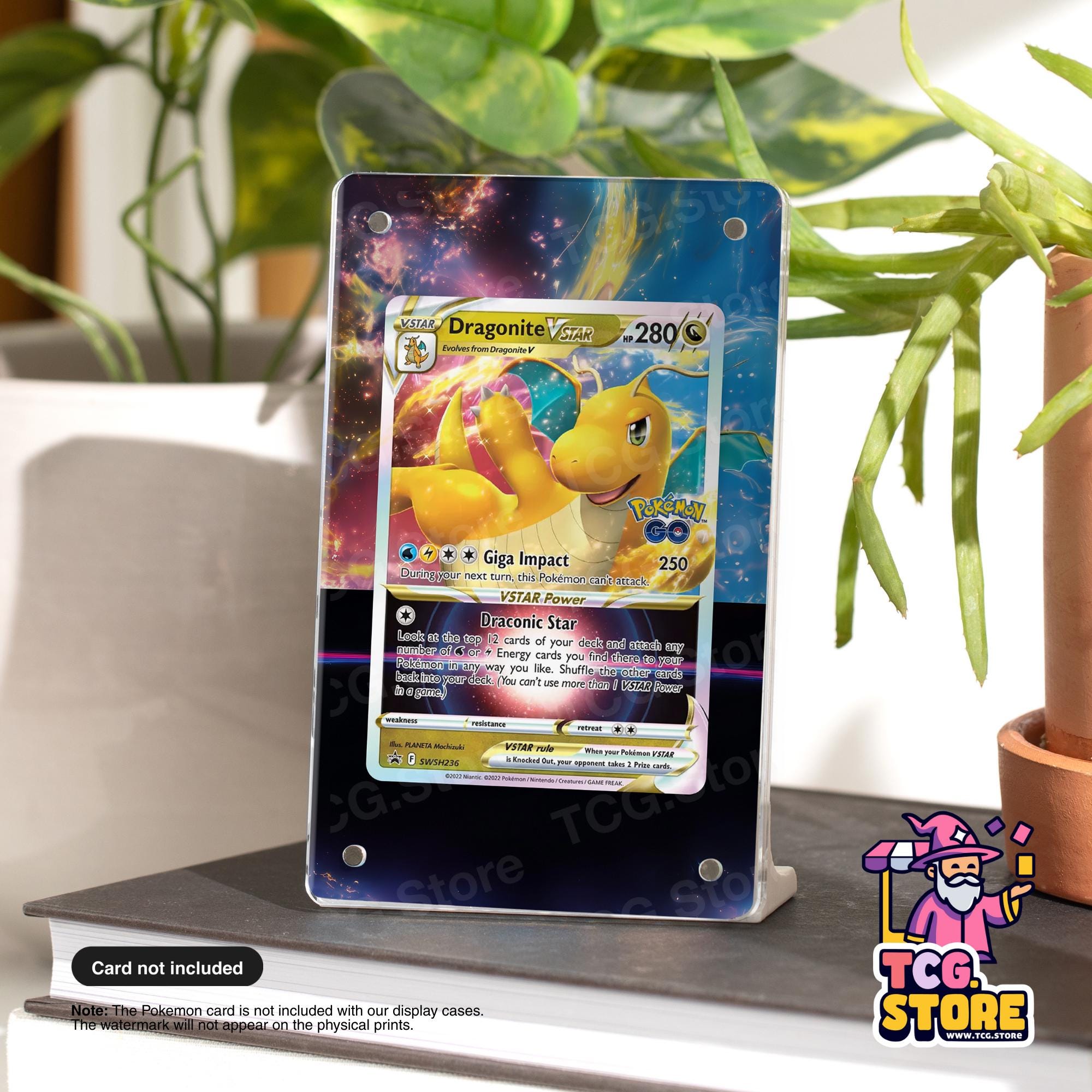 A dragon-themed Pokémon card is displayed on a stand, surrounded by plants and a potted plant.